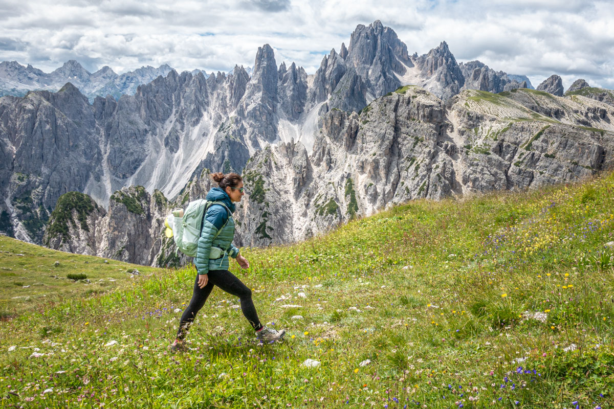 A woman hikes through a grassy expanse in the Dolomites, Italy