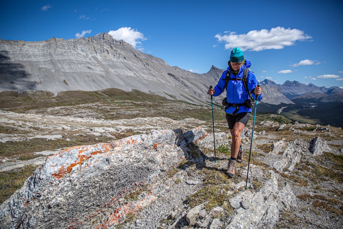 A woman hikes over rocky terrain in hiking boots