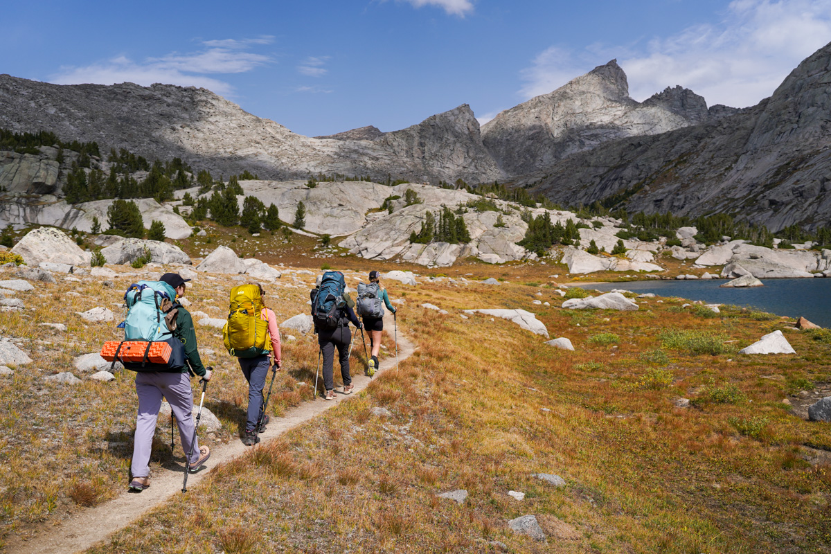 A group of friends hike through a mountain pass.