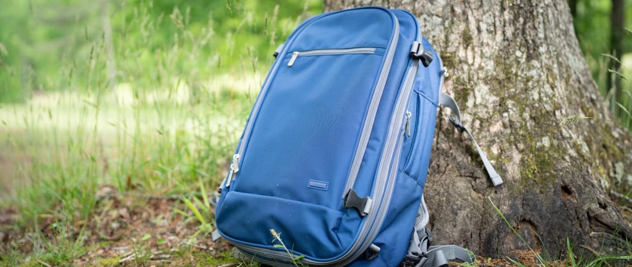 An Amazon carry on backpack rests on a tree trunk.