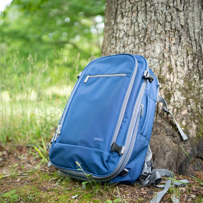 An Amazon carry on backpack rests on a tree trunk.