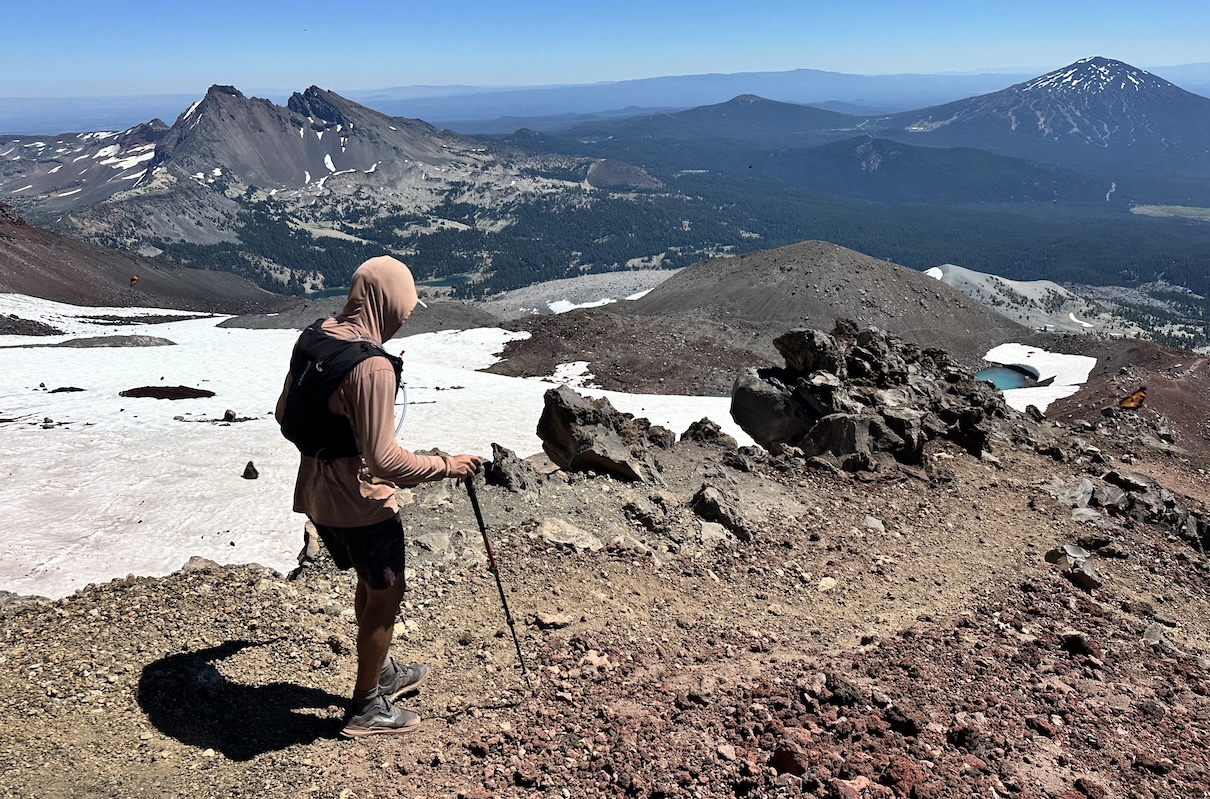 A hiker traverses a rocky trail on top of a mountain.
