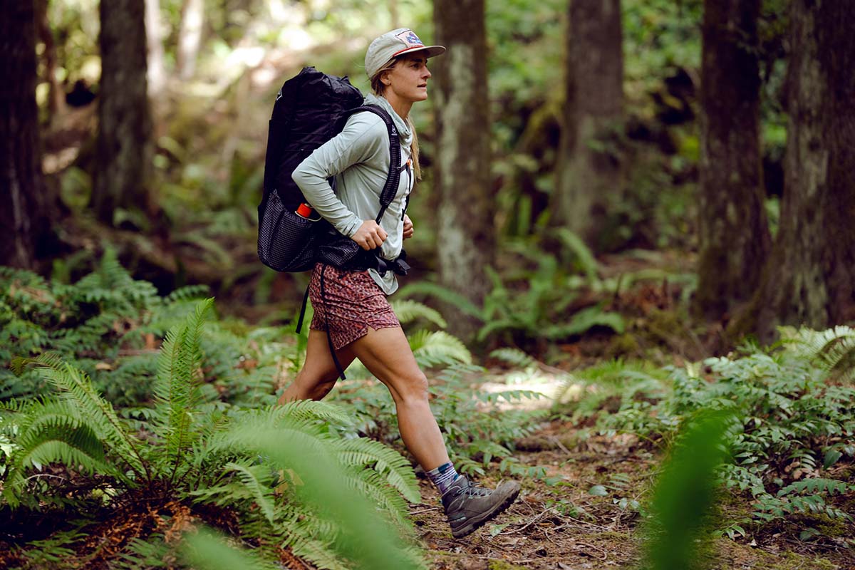 A woman hikes in a forest with the La Sportiva TX Hike Mid Leather GTX