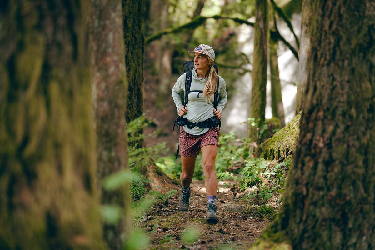 A woman hiking in a forest with the La Sportiva TX Hike Mid Leather GTX