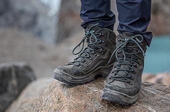 A closeup of the Lowa Renegade GTX Mid hiking boot while standing on a rock next to a lake