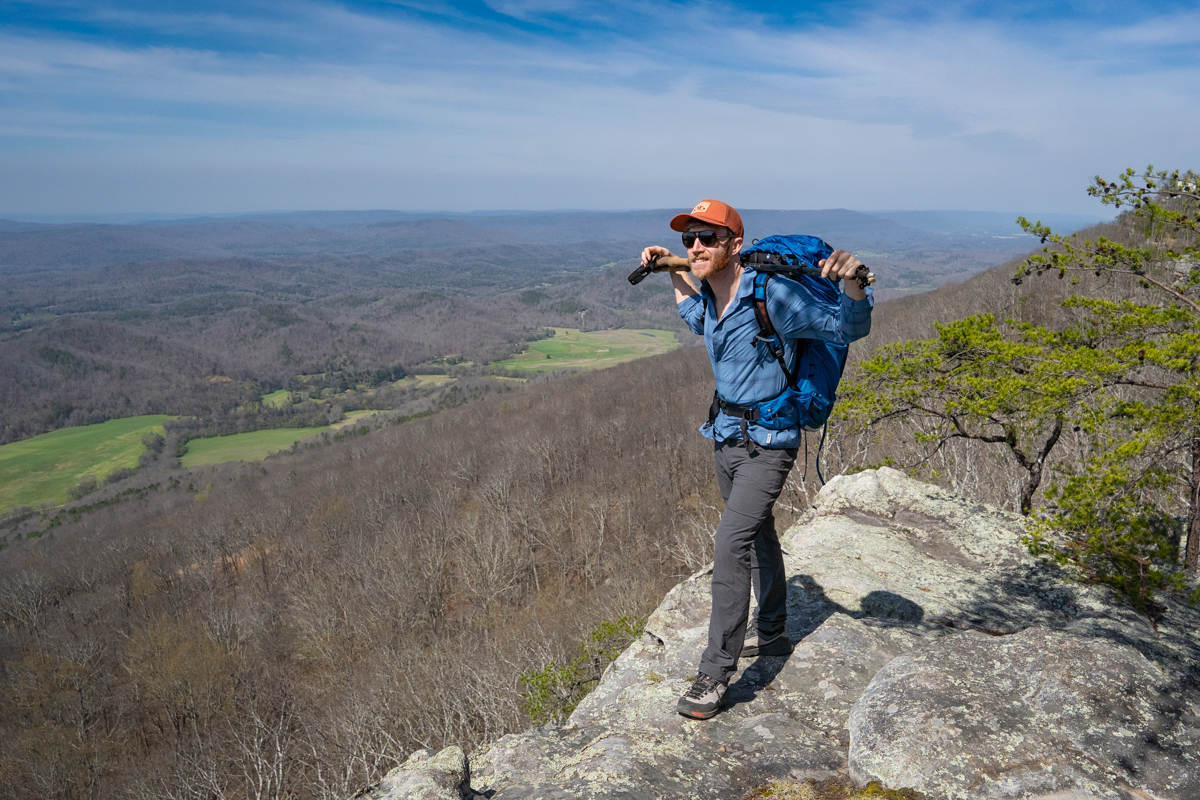 A man stands at an overlook wearing a backpack