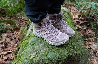 A pair of hiking boots standing on a mossy rock