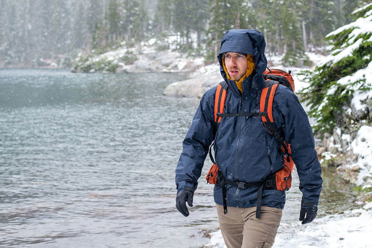 A man with his hood up hikes in winter weather.