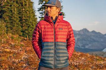 A hiker stands in the mountains wearing his Patagonia down sweater jacket.