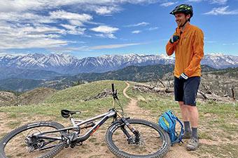 A mountain biker stops to zip up his Patagonia Houdini wind breaker. 