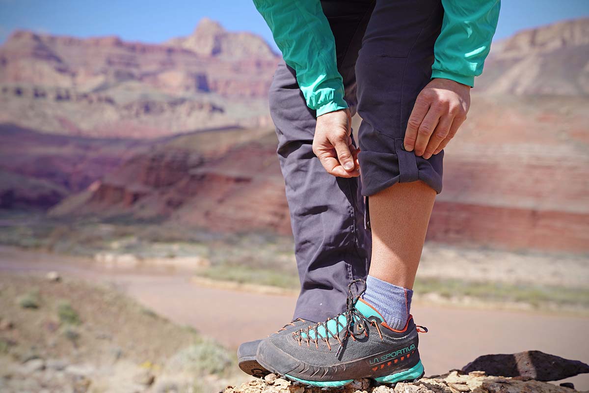 a woman rolls up her pant leg in the desert