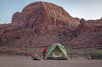 A tall, green tent is pitched in the red rock canyons of Utah.