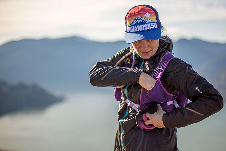 A long distance runner uses a pocket on their running vest.