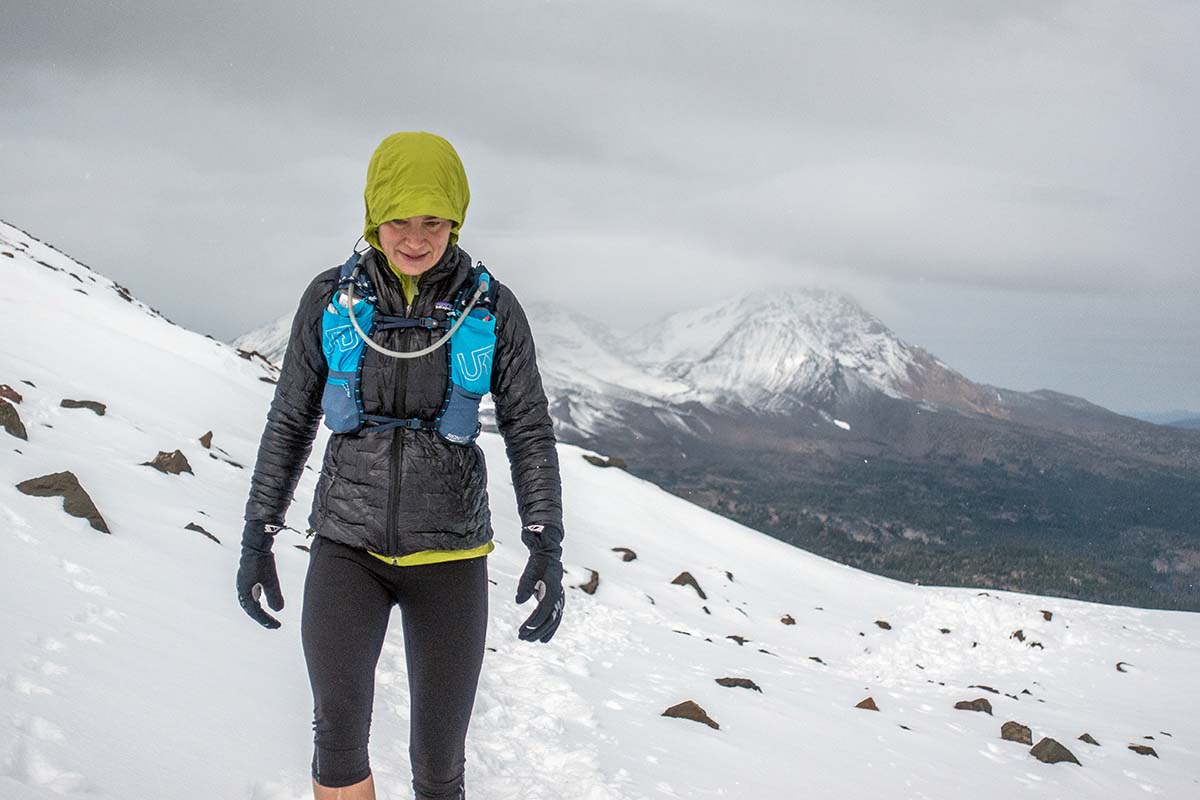 a woman walks through the snow on a peak 