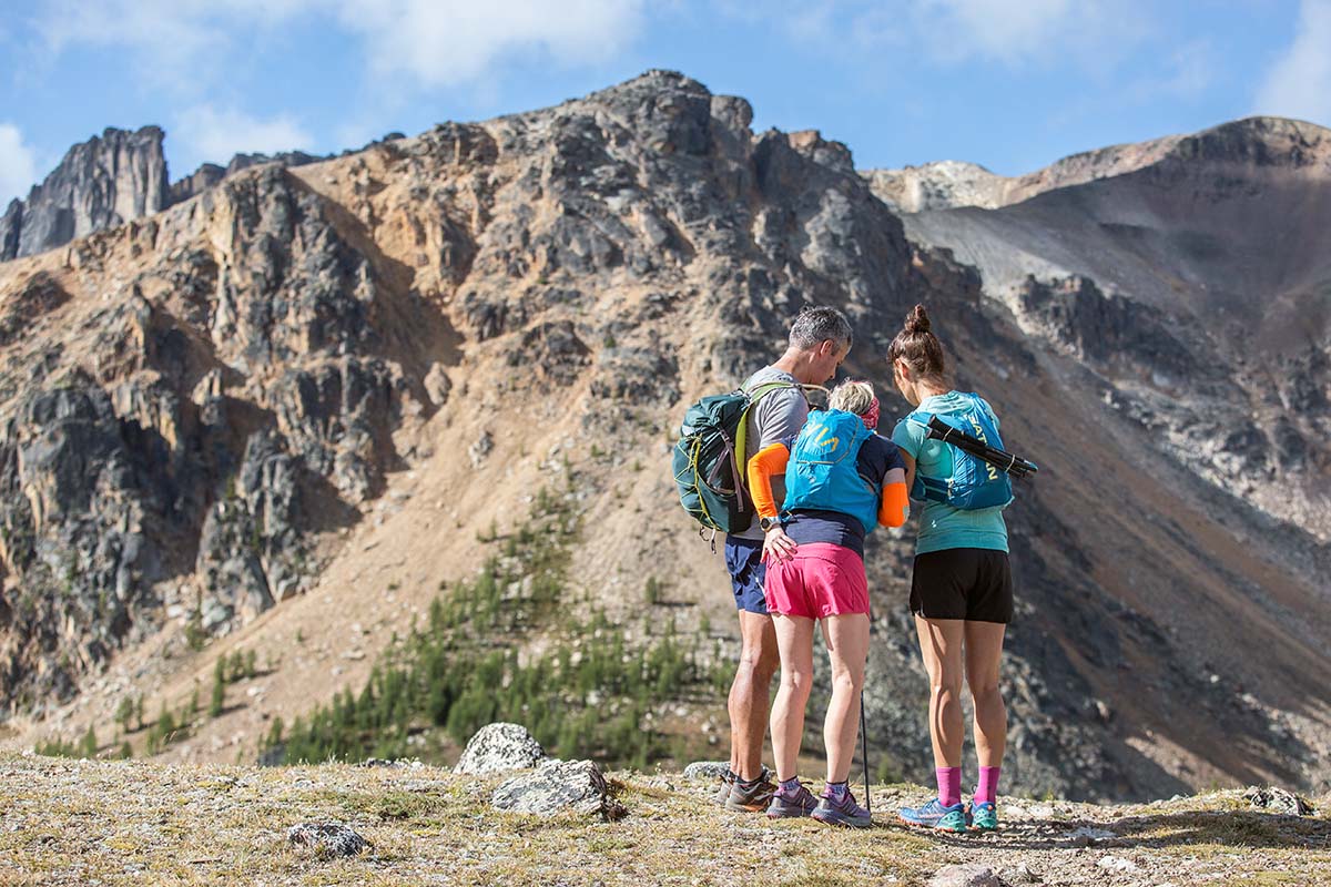 Three runners look at their GPS together while out on the trail