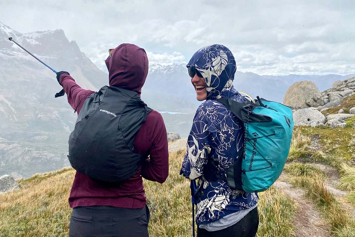 Two hikers wear running packs on a rainy mountain hike.