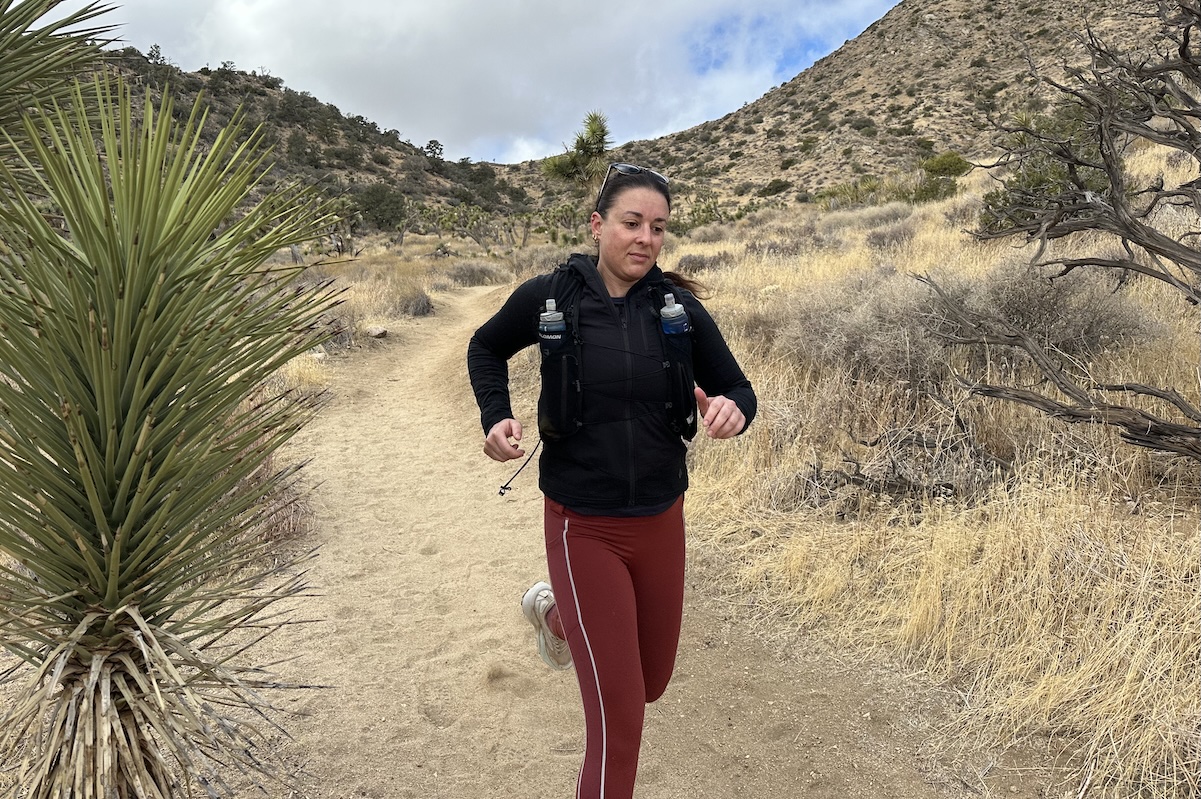 a woman runs down the trail in the desert