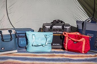 A group of soft coolers lined up in front of tent