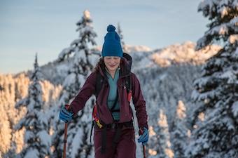 A woman on skis skins up a hill toward the camera