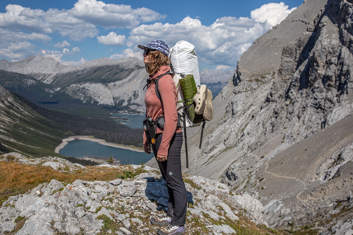 a woman stands on a ridgeline in the mountains