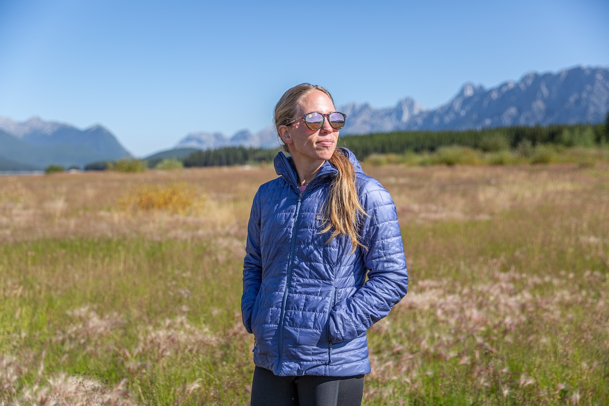 A woman stands in a field wearing a synthetic jacket
