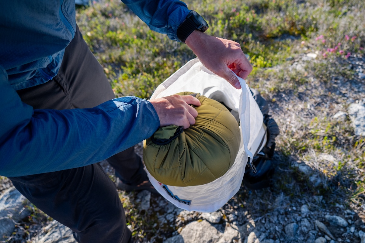 A camper stuffs their synthetic jacket into a stuff sack.