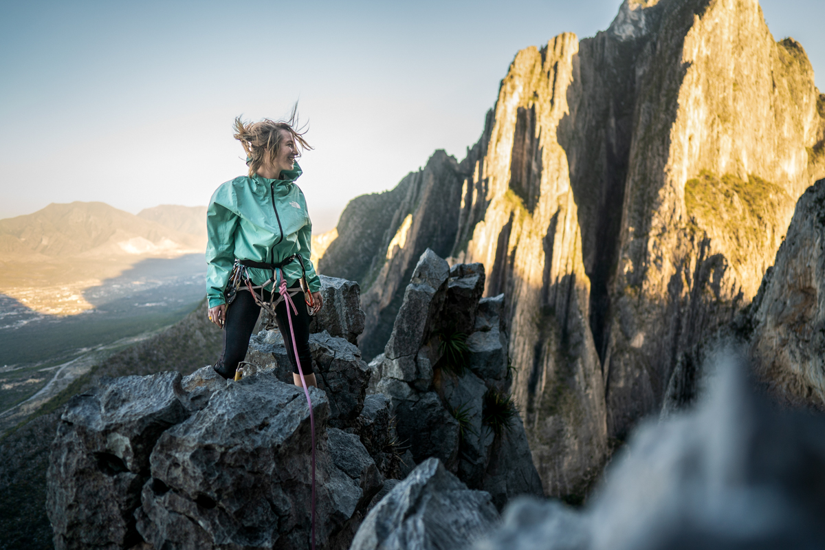 A woman standing on a rock wearing a windbreaker jacket