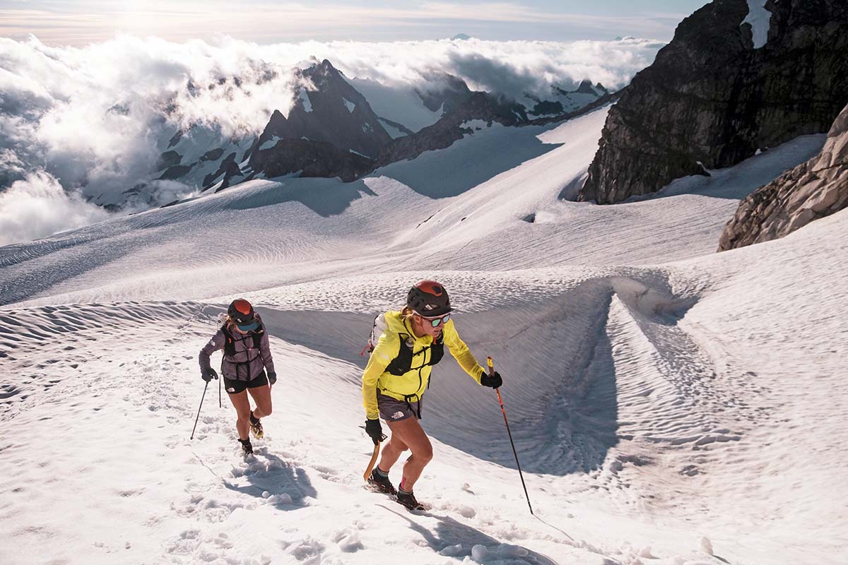 Two hikers move up a snowy, sunny slope.