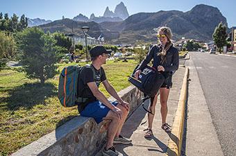 Two travelers in El Chalten, Argentina, pause to chat with their Topo Designs and Cotopaxi packs