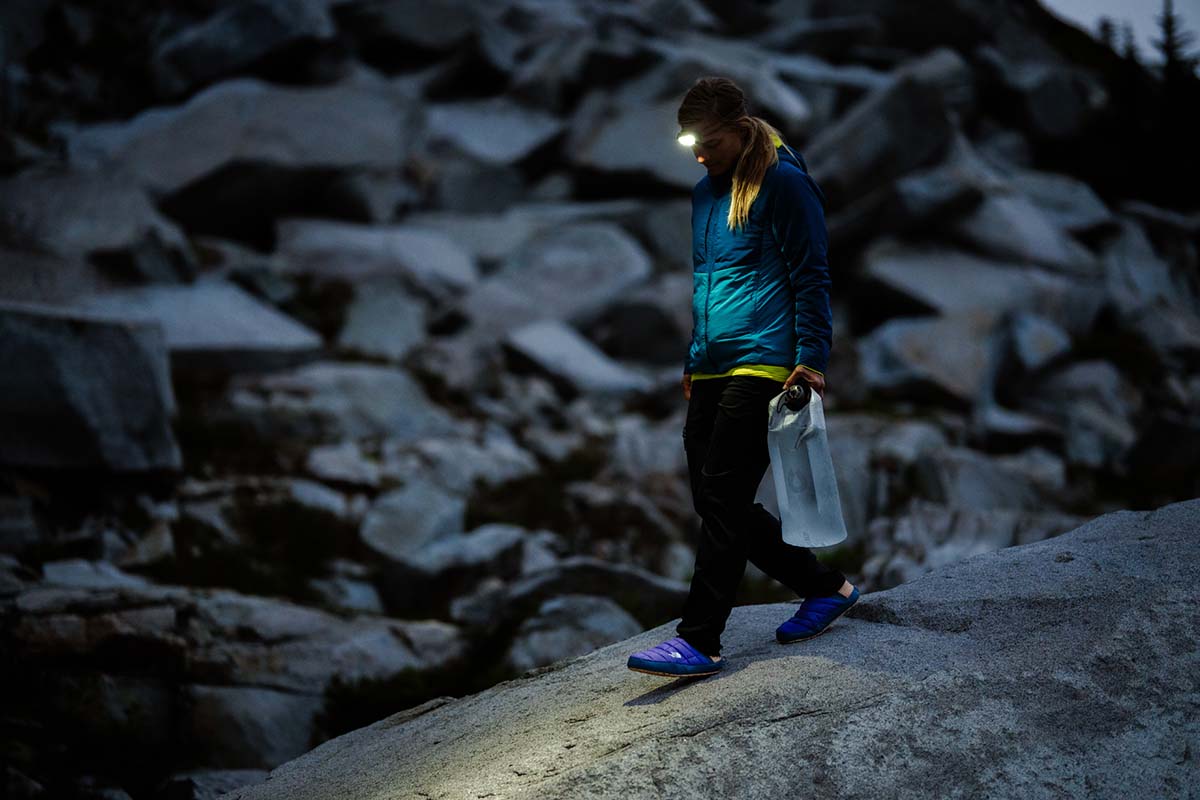 A woman walking to get water with a headlamp