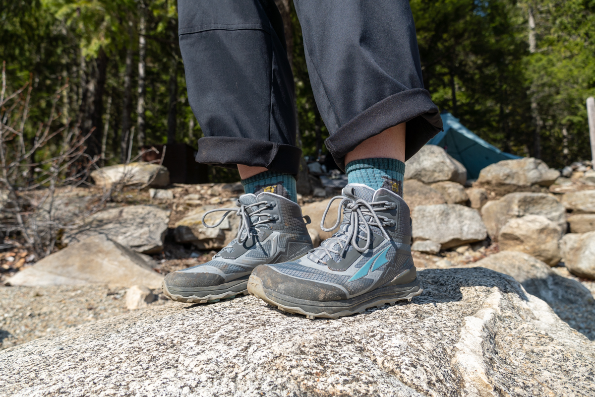 A hiker stands on top of a rock in their hiking boots.