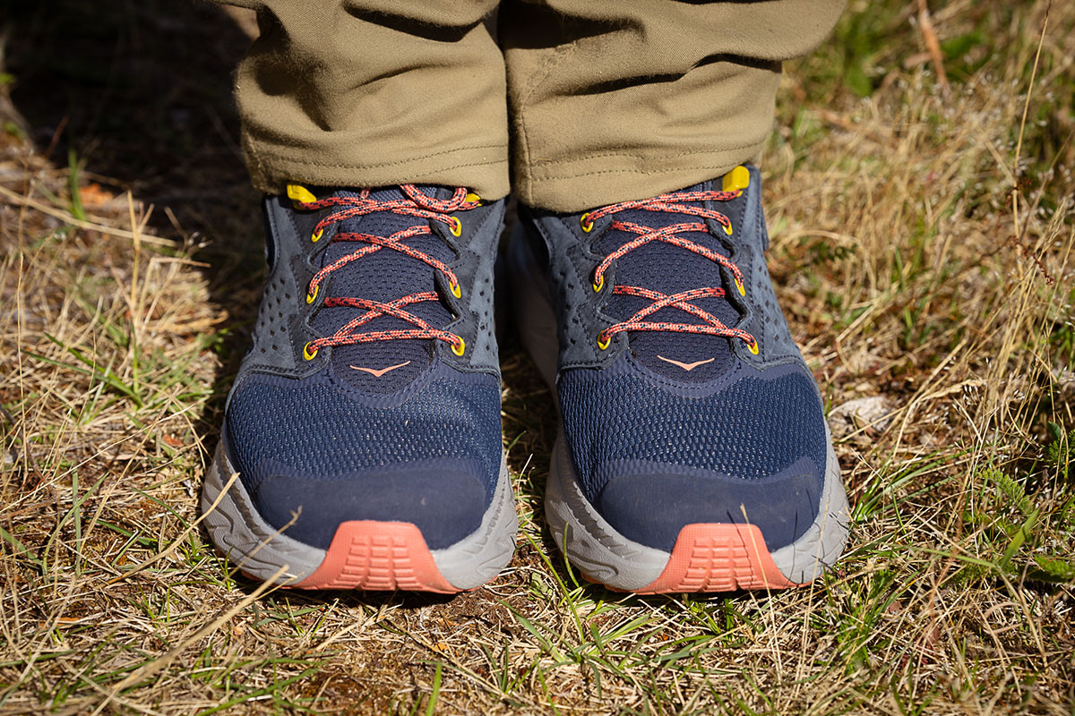 A pair of hiking boots in purple, salmon, and bright pink colors.