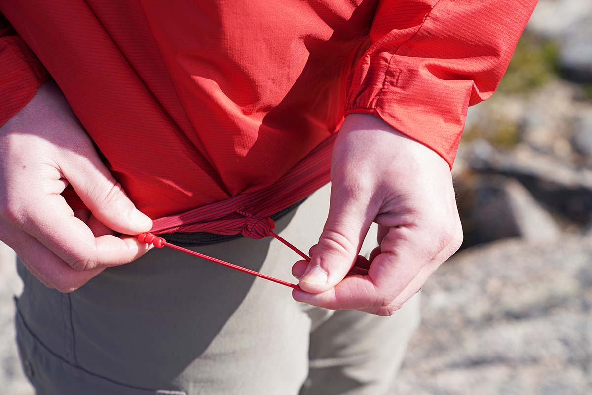 A tester illustrates the stretchy elastic cinch on the bottom of a windbreaker.