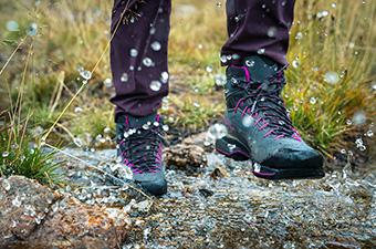 A hiker splashes through a puddle in their favorite hiking boots.