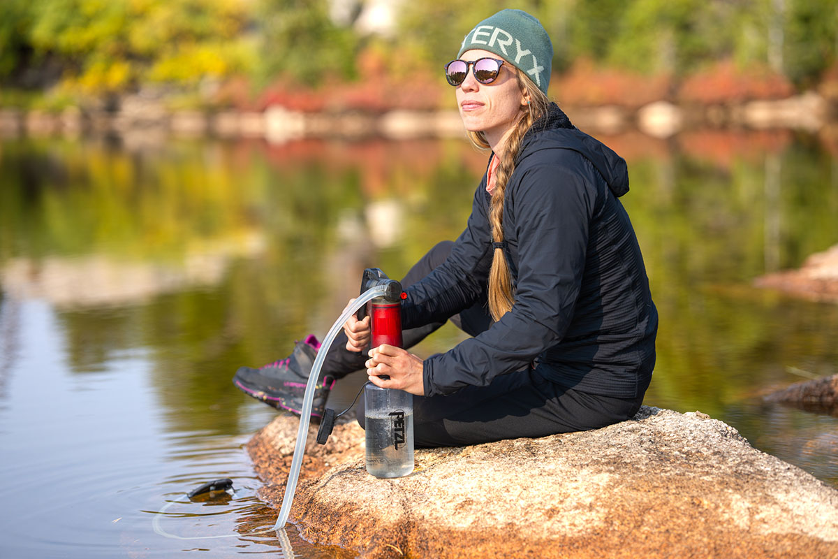 A woman filtering water in a synthetic jacket