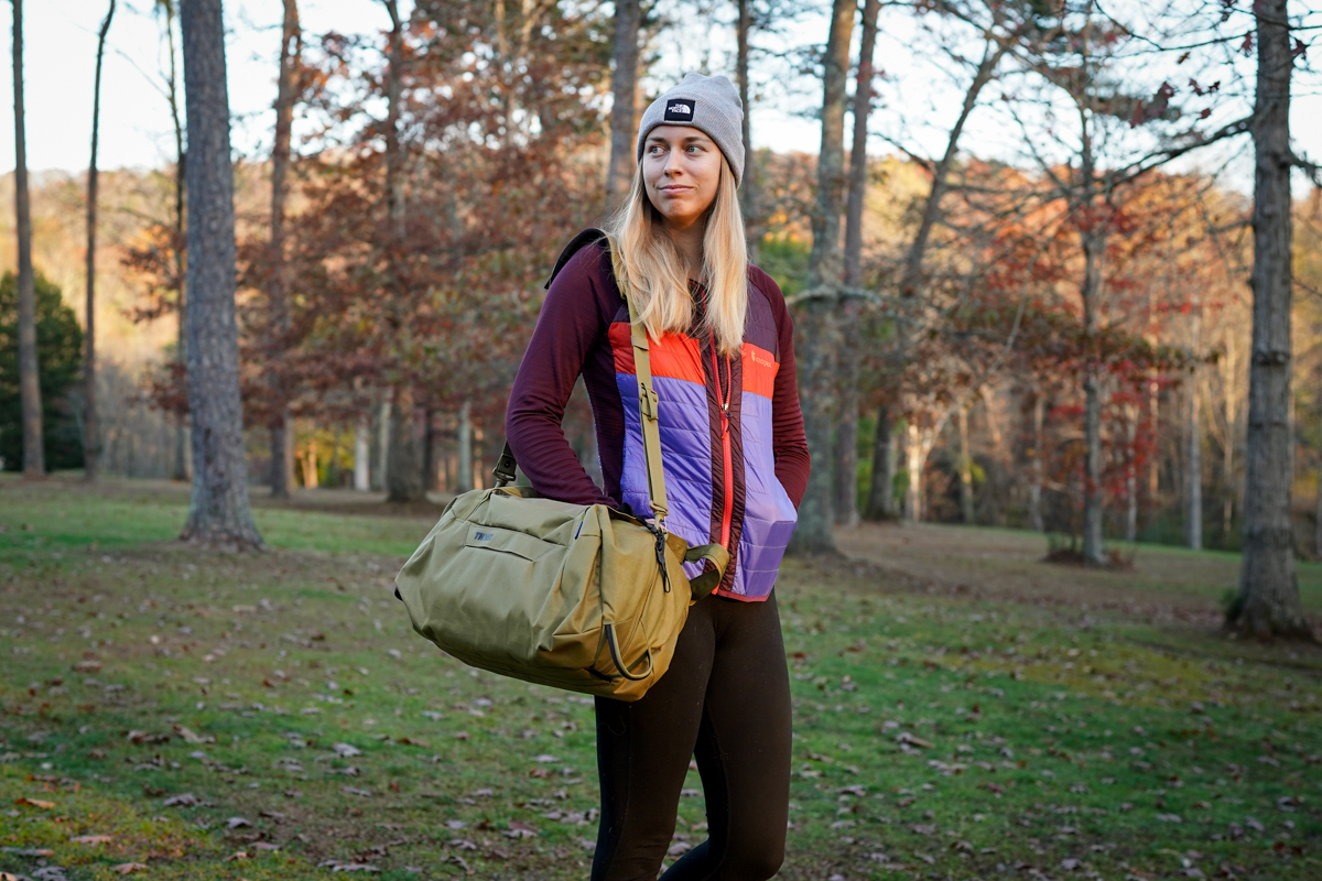 A woman carrying a duffel in a synthetic jacket