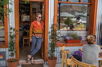 A woman standing in a cafe doorway wearing the Vuori Miles Jogger