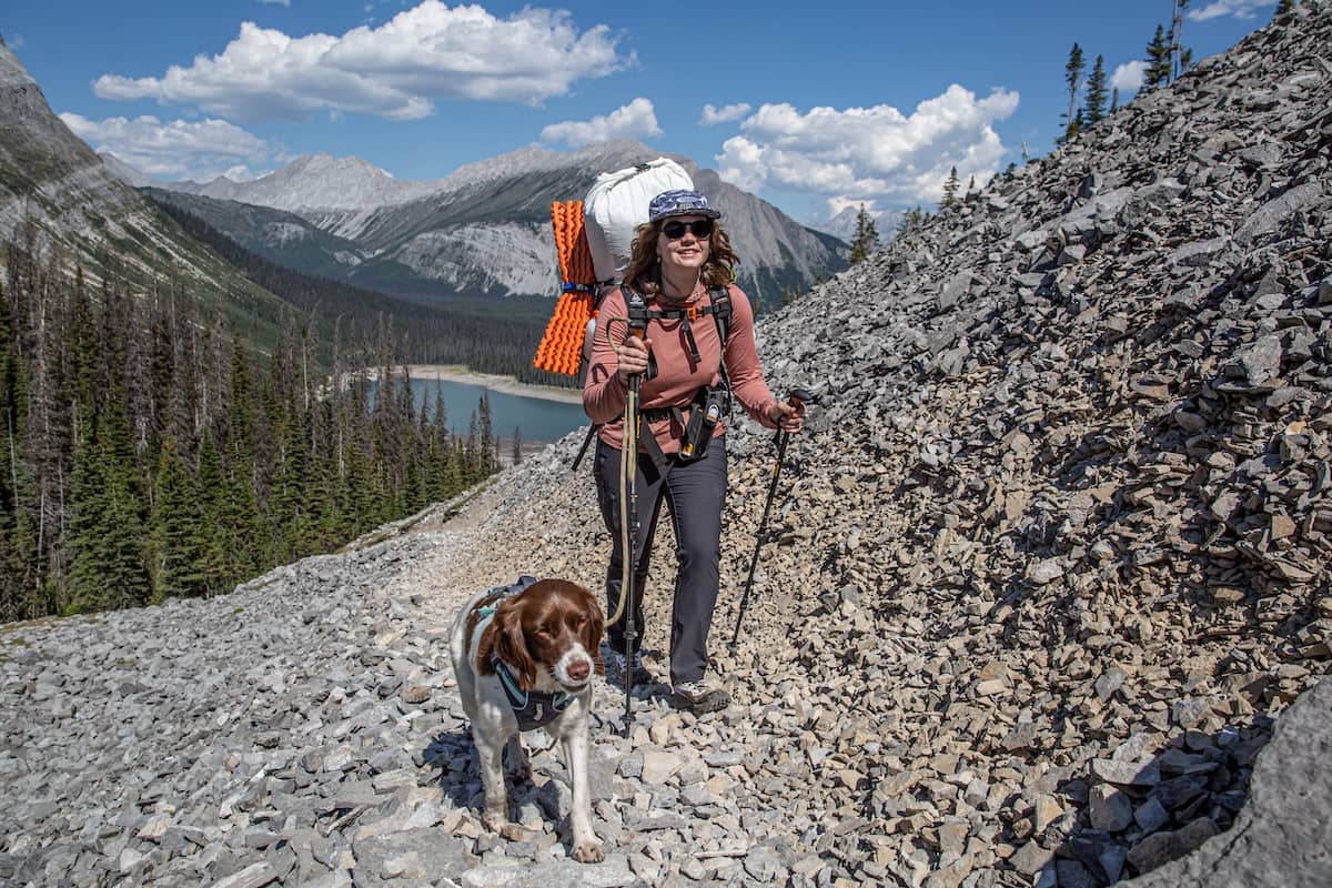 A woman and her dog hike up a rocky trail