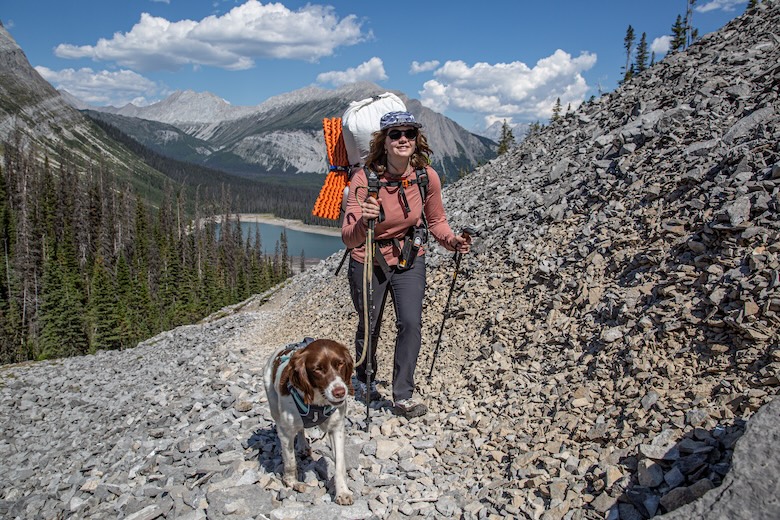 A woman and her dog hike up a rocky trail