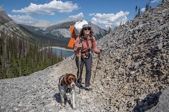 A woman and her dog hike up a rocky trail