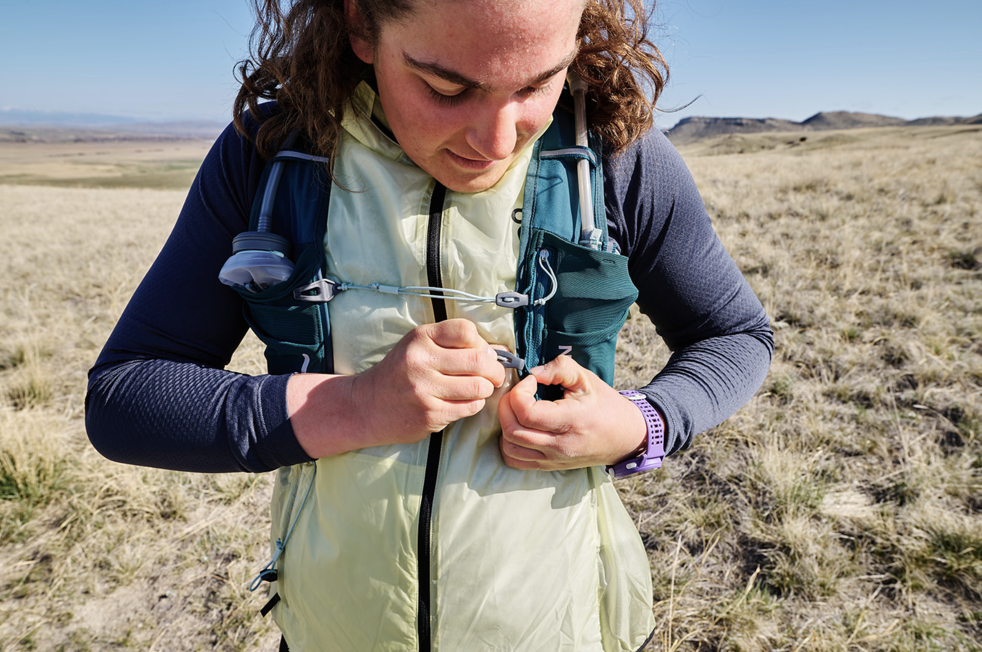 a woman adjusts the straps on a hydration pack